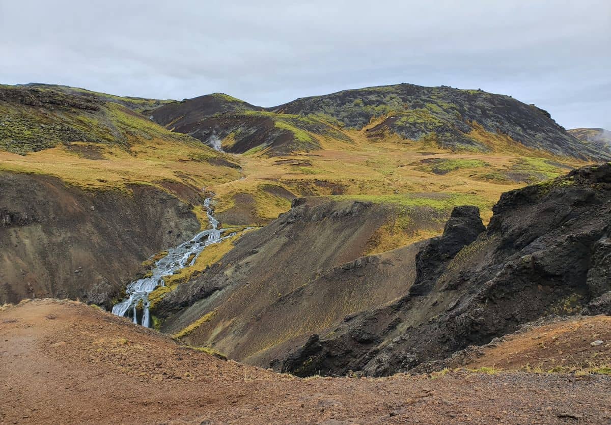 Picture of Icelandic landscape with a green and rock covered mountains with a waterfall