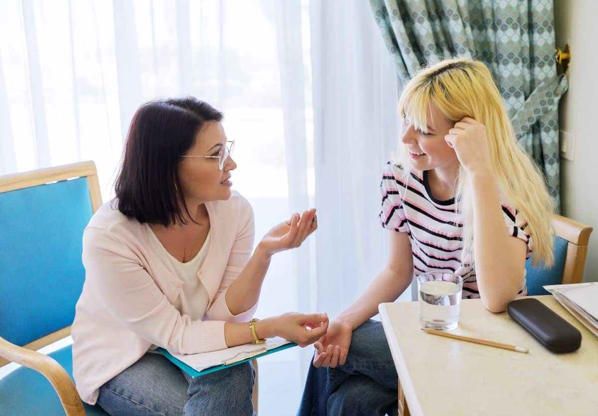 A therapist and a teen sitting at a table in discussion