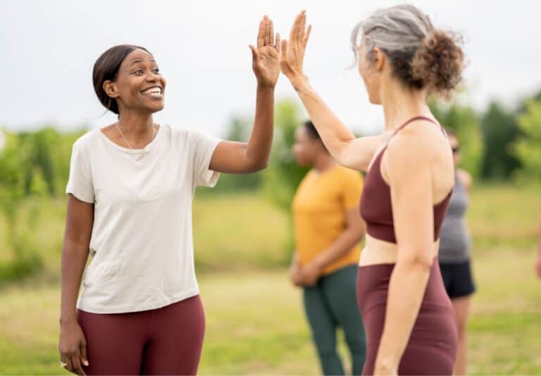 Two moms high fiveing each other in a sports field.