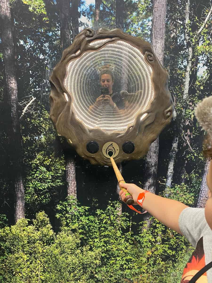  Reflection of a mom wearing wolf ears at a wooden touch point for a wand game at Great Wolf Lodge