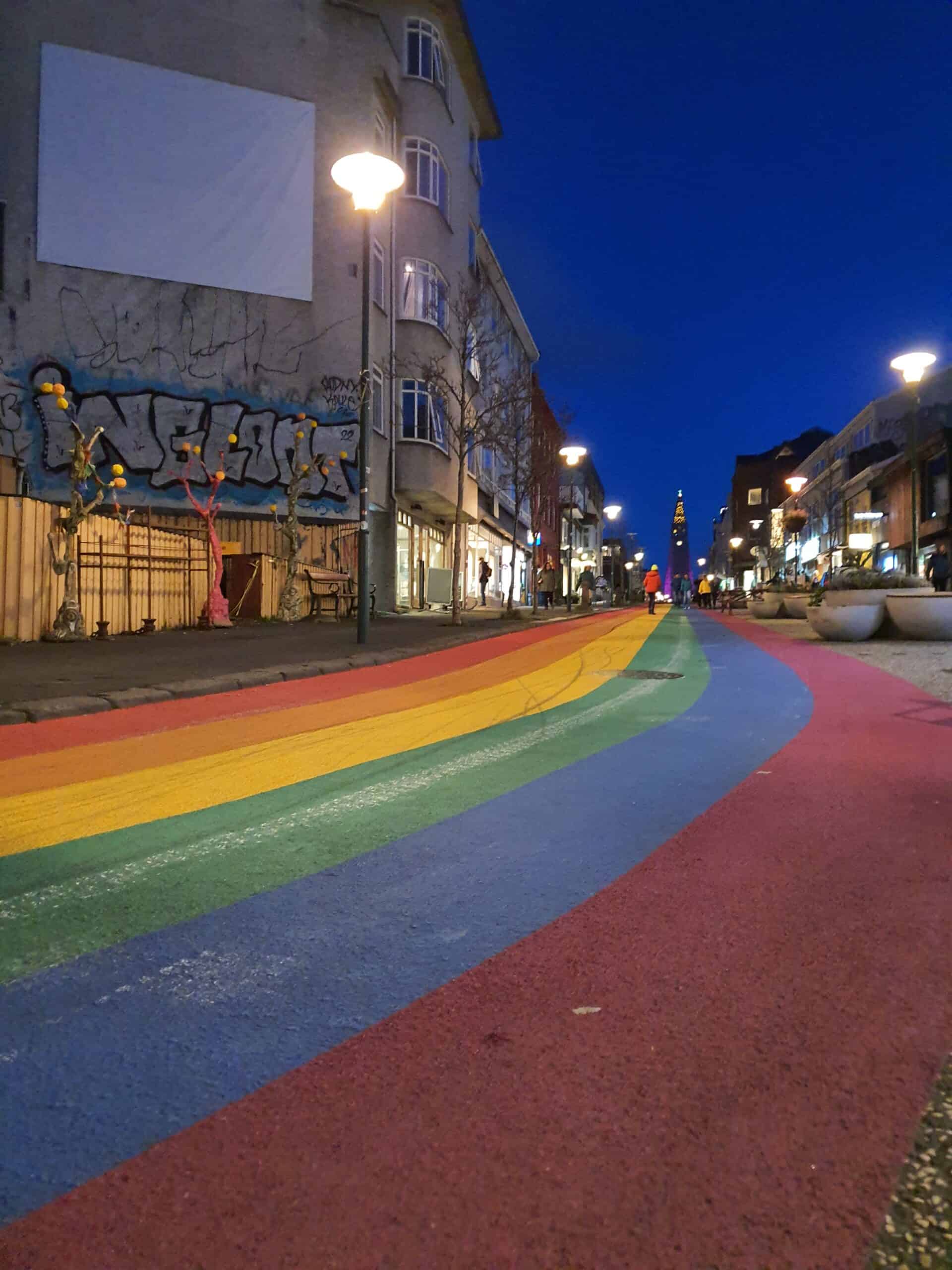 A view of downtown Reykjavik at night with a rainbow painted on the street.