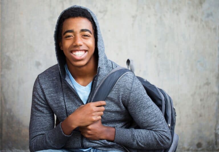 Teen boy in hoodie with a backpack smiling