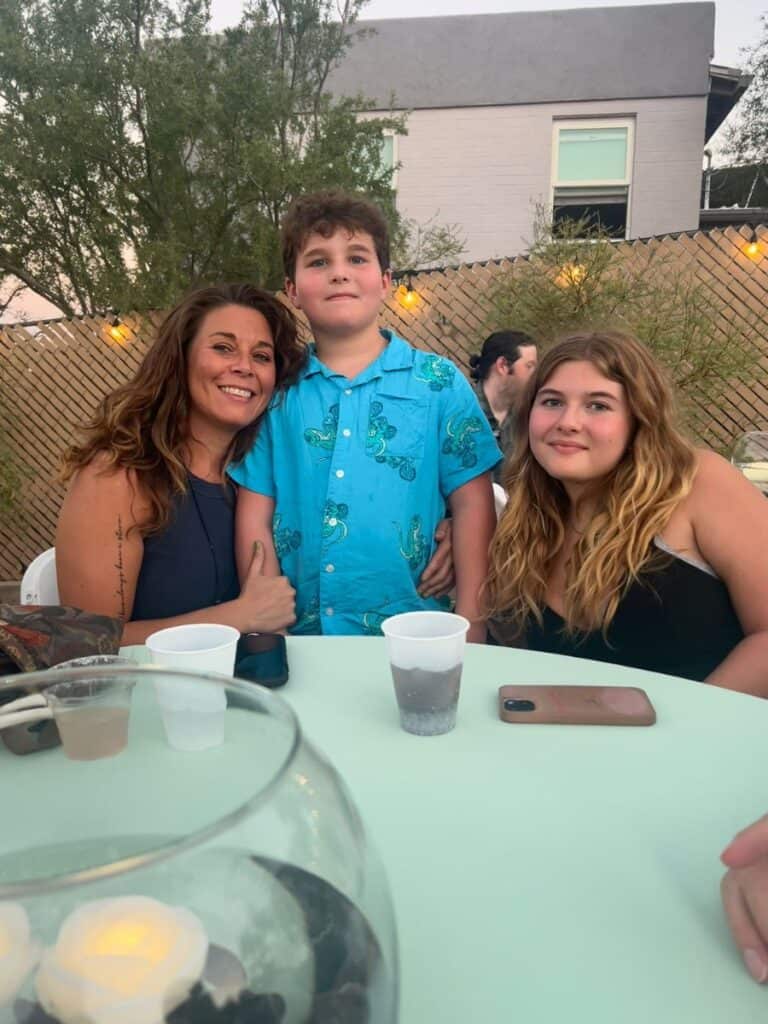 Single mom, tween son and teen daughter posing at a dinner table