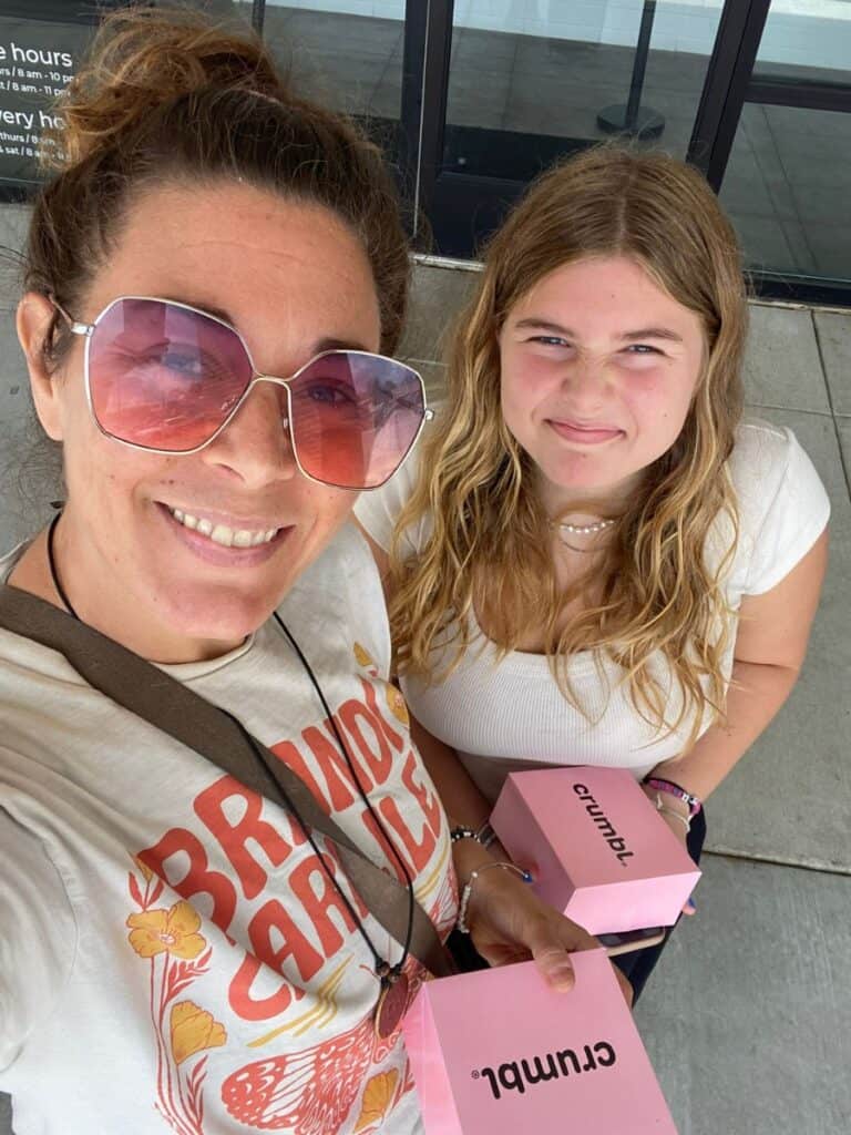 Single mom smiling with her teenage daughter with a box of Crumbl cookies