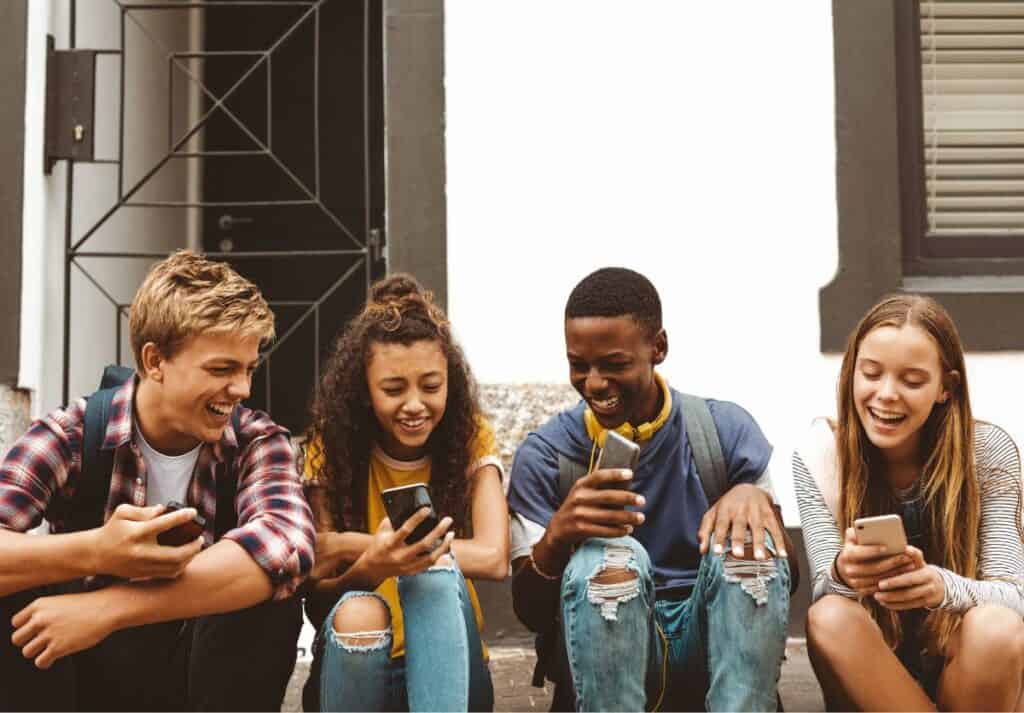 4 teens sitting on a stoop texting slang