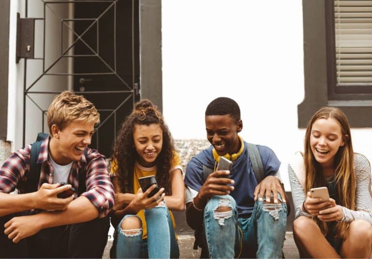 4 teens sitting on a stoop texting slang