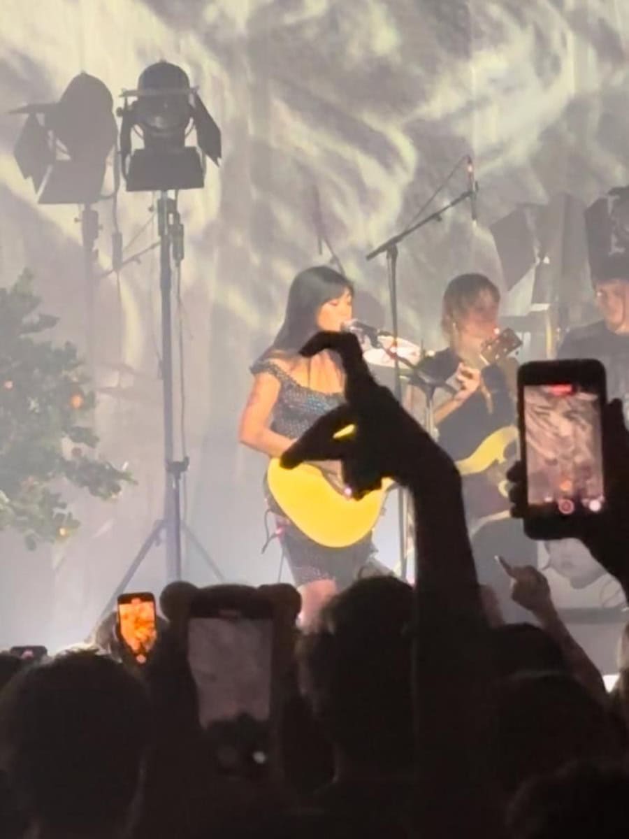 Beabadoobee live at a concert with a fan making a heart gesture with hand.