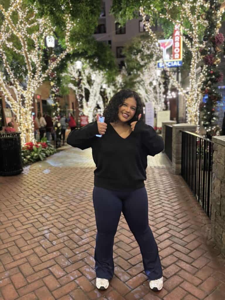 Teenage girl with two thumbs up on a tree-lined walkway outside Harbor Social in the Gaylord
