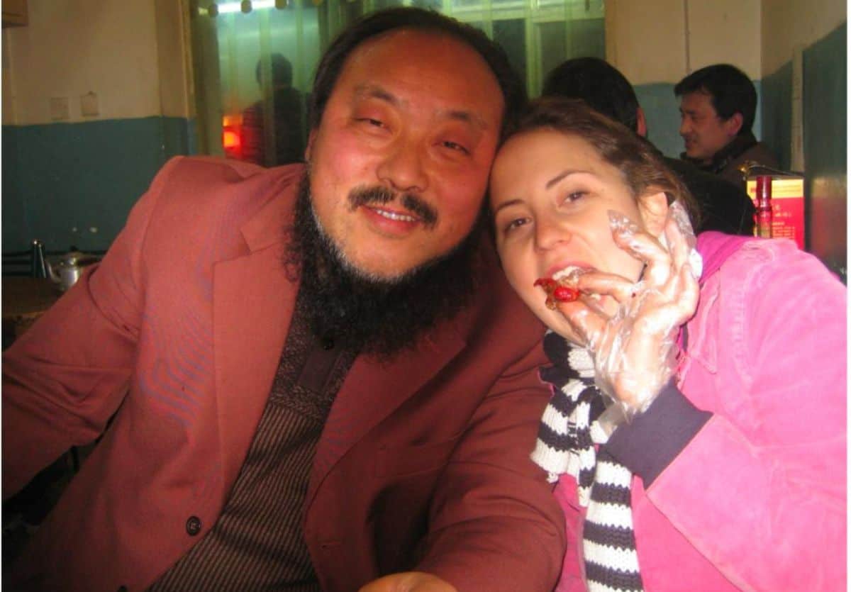 A young woman holding a crayfish with plastic gloves and an older man at a restaurant