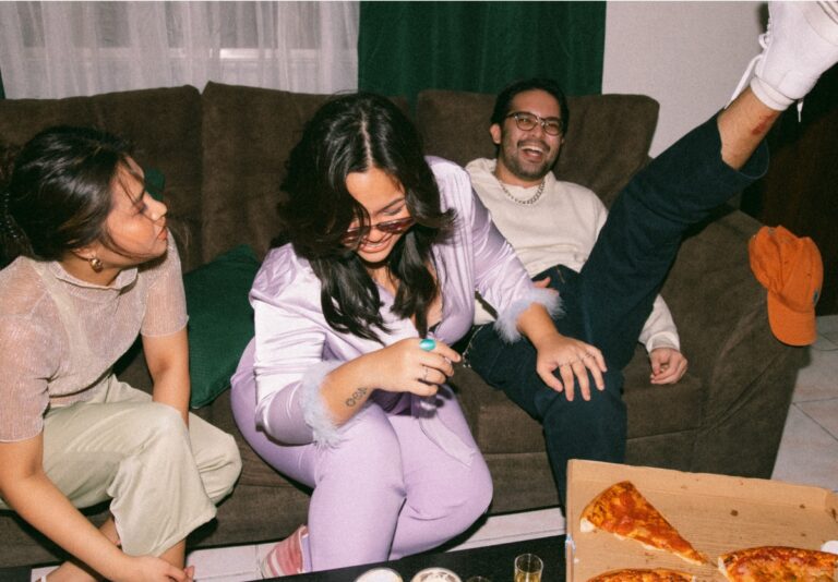 Three teenagers on a couch at a party.