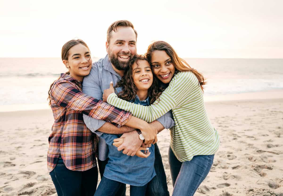 A family with teens smiling on the beach on vacation