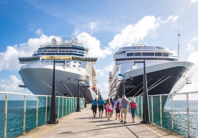 Two cruise ships docked with families walking down the pier